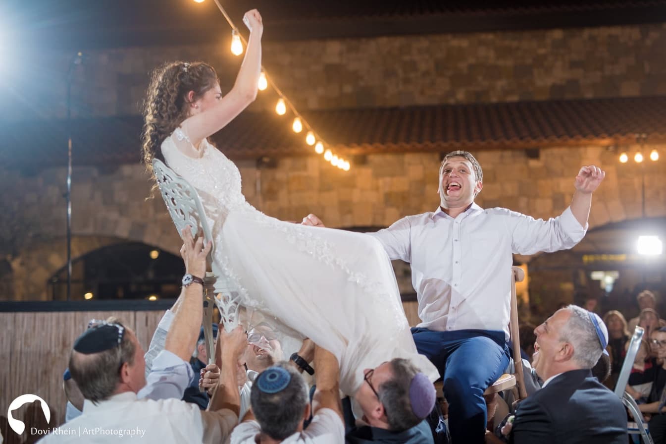 החתן והכלה מורמים על כיסאות